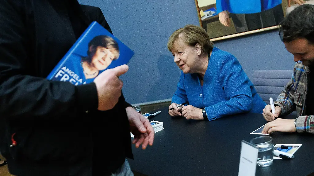 Angela Merkel signiert Kunstpostkarten ihres Porträts im Bode-Museum
